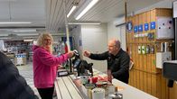 Asiakas ottaa vastaan kuitin huoltamon kassalla. 