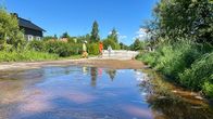Vesilätäkkö tiellä. Takana huoltomiehiä.