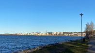 Lähikuvassa on syksyinen Vesijärvi Lahdessa. Pieniä aaltoja järvessä, järven rannalla kerrostaloalue. 