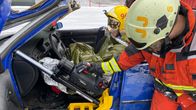 Kouluttaja käyttää hydraulista pelastuslaitetta simuloidussa liikenneonnettomuustilanteessa auton kuljettajan pelastamiseksi.
