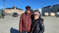 Mies ja nainen seisovat lähekkäin aurinkoisella torilla.