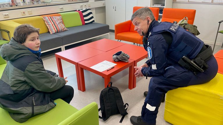 Kuvassa poliisi juttelee koululaiselle.