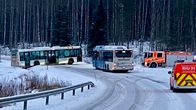En buss står tvärs över en landsväg. Bredvid väntar en annan buss och två brandbilar.