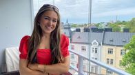 Kvinna i porträttbild på balkong med Helsingfors i bakgrunden.