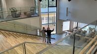 Kaksi henkilöä keskustelee aula- ja porrastilassa modernissa koulurakennuksessa.
