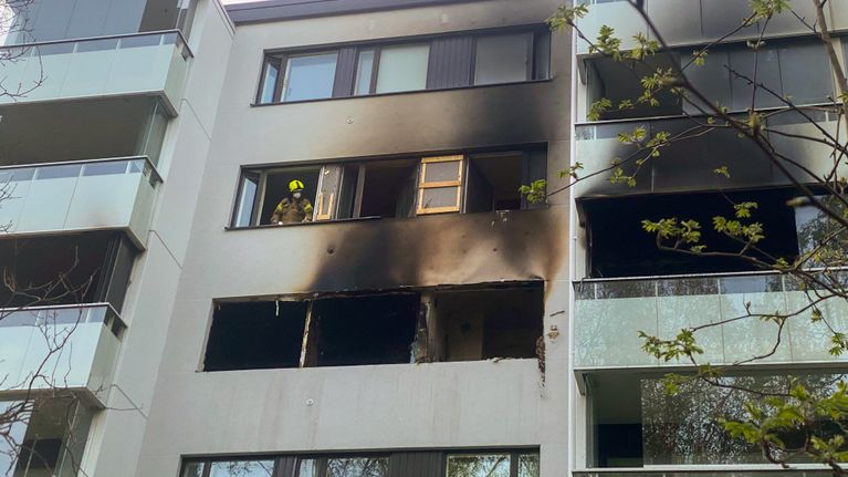 Palomies katsoo ulos palaneen asunnon ikkunasta.