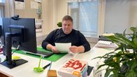 Mies lukee papereita toimistopöydän ääressä.