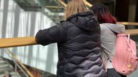 Kaksi nuorta nojaa kaiteeseen kauppakeskuksessa.