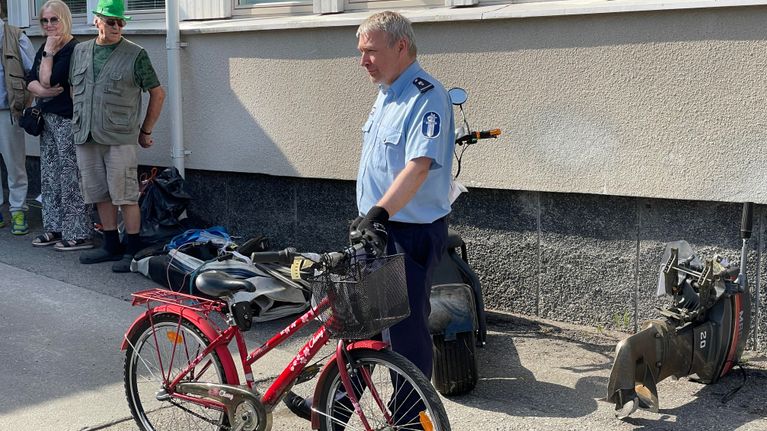 Lieksan poliisi esittelee löytytavarahuutokaupassa tarjolla ollutta lasten polkupyörää poliisilaitoksen pihamaalla.
