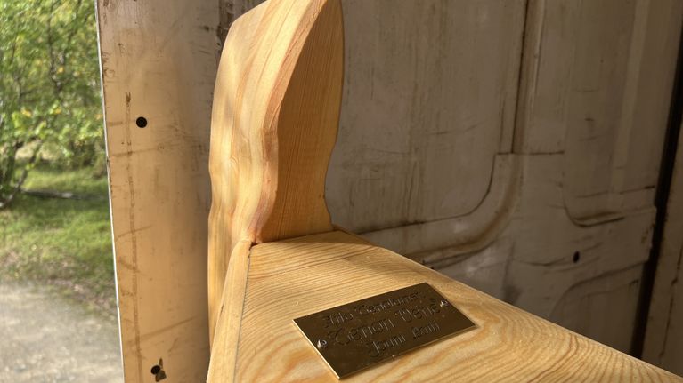 Vaalea puinen jokiveneen kokka, jonka kŧlessä on metallilaatta, jossa teksti “Aito Tenolainen Tenon vene Jouni Laiti 20.8.2026 Utsjoella..