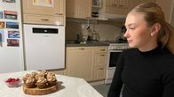 Nuori nainen katsoo pöydällä olevia makeita leivonnaisia, joiden vieressä on kupillinen vadelmia.