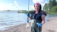 En kvinna står vid vattenbrynet iklädd vadarbyxor.