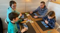 Sveitsiläiset Andrea Fink ja Kevin, Eero ja Nora Bitterli korttipelin parissa mökissä.