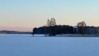 Järven jäätä ja taustalla saari, jossa vanha tuulimylly.
