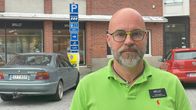 Mies katsoo kameraa, taustalla autoja parkissa.