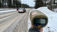 Nopeusvalvontatutka osoittamassa talviselle tielle, jossa kulkee autoja.