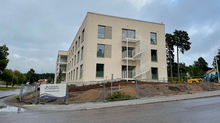 Ett ljusgult flerbostadshus med tre våningar och utvändiga trappor.