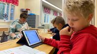 Kolmasluokkalaisia poikia oppitunnilla, etummaisella on tabletti ja oppikirja.