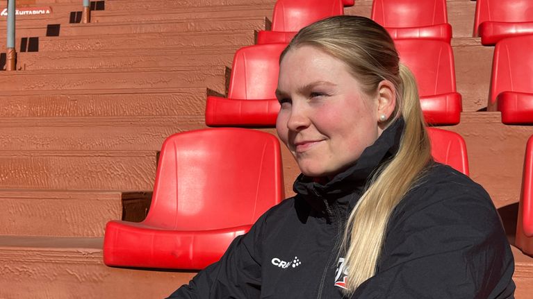 Pesäpalloilija Emilia Linna istuu aurinkoisen Joensuun pesäpallostadionin katsomossa.