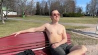 Mies nautti aurinkoisesta kevätpäivästä puiston penkillä.