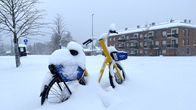 En gul stadscykel har begravts i en snödriva under ett snöoväder.