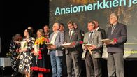 Ansiomerkkien ja huomionosoitusten saajat yhteiskuvassa palkitsemistilaisuudessa poroparlamentissa.