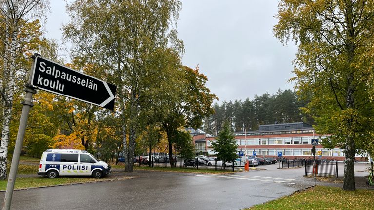 Salpausselän koulu syksyisessä maisemassa, etualalla liikennemerkki ja poliisiauto.