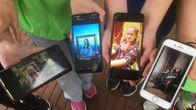 Lapset esittelevät uudella tavalla ottamiaan luokkakuvia kännyköiden ruudulla. 
