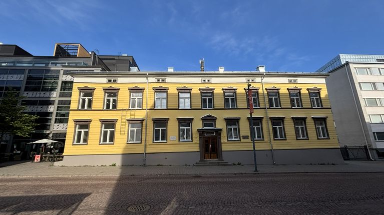 Ett gult trähus omgiven av betonghus.