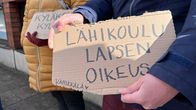 Ihminen pitää kädessään pahvin palasta, missä lukee: Lähikoulu on lapsen oikeus.