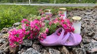 Hautakynttilöitä, kukkia ja pieni violetti sandaali tienpintareella.