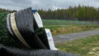 Rullalla oleva tekonurmi. Taustalla aidattu jalkapallokenttä.