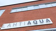 Lahti Aqua -kyltti punatiilisen rakennuksen seinässä, ikkunoita.