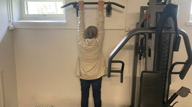 Dam stretchar i en ställning på gymet.