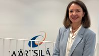 En person i ljus kavaj står framför en vägg med företagets logotyp och texten Wärtsilä.