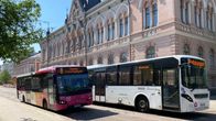 Etualalla kaksi linja-autoa ja takana vanha vaalea tiilirakennus.