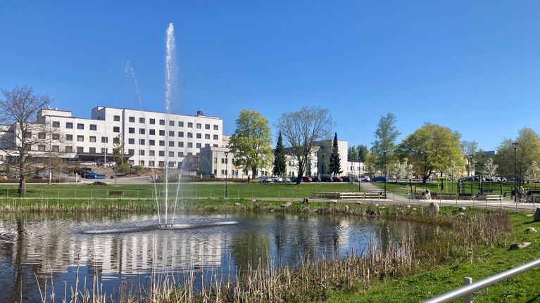 Valkoinen iso sairaalarakennus, jonka edessä olevassa lammikossa on toimiva suihkulähde.
