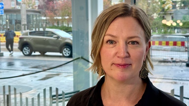 Kirjastopalvelujohtaja Niina Salmenkangas katsoo kameraan. Taustalla näkyy ikkunasta ulos, jossa sataa.