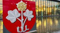 Muuramen isokokoinen puna-hopea-harmaa vaakuna vesialtaan päällä Muuramen kirjaston isojen ikkunoiden edessä.