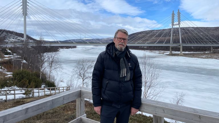 Henkilö poseeraa talvisessa maisemassa Tenojoen ja Saamen sillan edustalla 30.4.2026 Utsjoella.