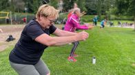 Nainen jumppaa yhdessä muiden kanssa puistossa.