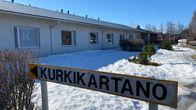 Valkoinen rivitalo taustalla, etualalla "Kurkikartano" -kyltti.