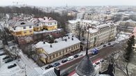 Vy över ett vinterklätt bostadsområde i Åbo, Finland, med äldre byggnader och bilar längs gatan. I bakgrunden syns stadens stadssiluett.