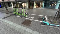 Sähköpotkulautoja on pysäköitynä valkoisella rajatussa parkkiruudussa. 