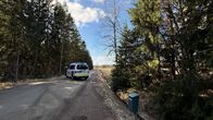 Poliisiauto poikittain keskellä hiekkatietä.