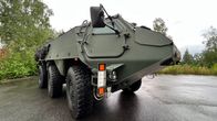 Kuusipyöräinen 6x6 harmaanvihreä panssariajoneuvo seisoo asfaltilla Hämeenlinnassa Patrian piha-alueella.