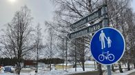 Kaksi katukylttiä, joiss ylemmässä lukee Pogostan koulu ja alemmassa Ilomantsin lukio. Kylttien alapuolella kevyen liikenteen väylän merkki.