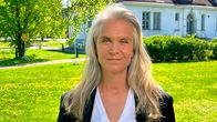 Kristiina Komulainen. Komulaisen takana on keväisen vihreä pihamaa ja valkoinen rakennus.