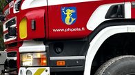 Lähikuvassa on punaisen paloauton ohjaamon kylki. Kyljessä on logo.