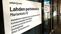 Lähikuvassa on valkoinen kyltti sisäänkäynnin ulko-ovessa. 
